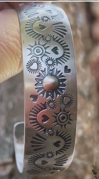 Silver cuff bracelet etched with hearts and symbols